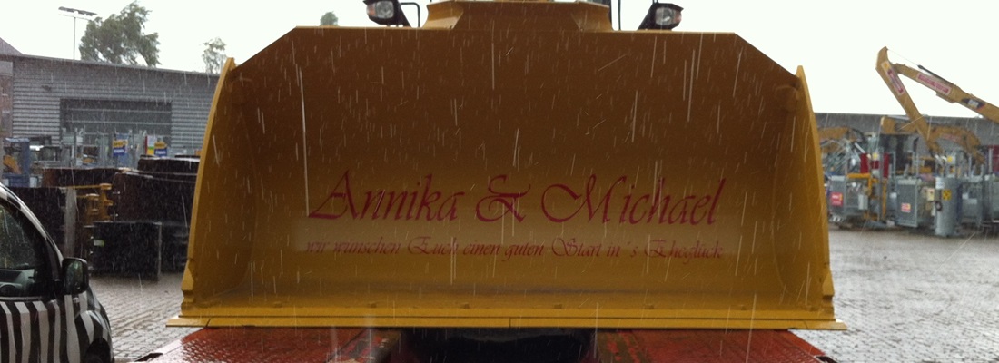 Gelber Bagger mit roter Beschriftung „Annika & Michael“ – individuelle Fahrzeugbeschriftung von Folien Fischer Hamburg für besondere Anlässe in Bergedorf, Wentorf, Reinbek, Geesthacht,schwarzenbek, Lüneburg und Glinde