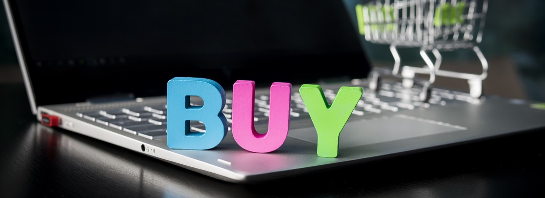 Online-Shopping Symbol – bunte Buchstaben BUY auf Laptop-Tastatur mit Mini-Einkaufswagen