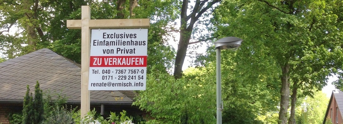 Ein Verkaufsschild steht an einem Gartenzaun. Auf dem Schild steht „Exclusives Einfamilienhaus von Privat ZU VERKAUFEN“ in großen, roten Buchstaben. Darunter sind Kontaktinformationen wie Telefonnummern und eine E-Mail-Adresse angegeben. Im Hintergrund sind grüne Bäume und ein Teil eines Hauses zu sehen. Ein Straßenlampenpfosten steht ebenfalls im Bild, und die Szene ist bei Tageslicht aufgenommen.