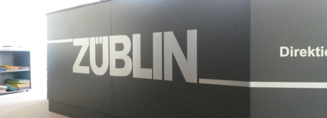 ZÜBLIN Schriftzug auf dunkler Wand im Büro, moderne Beschriftung von Folien Fischer Hamburg für Innenraumgestaltung in Bergedorf, Wentorf, Reinbek, Geesthacht, Lüneburg und Glinde.